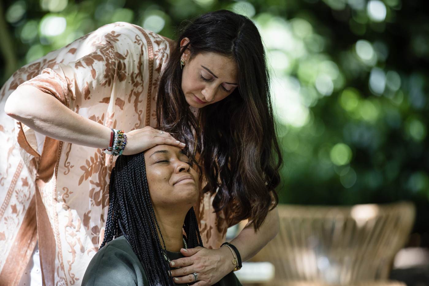 Lauren giving a healing session outdoors, her hands on a woman's head