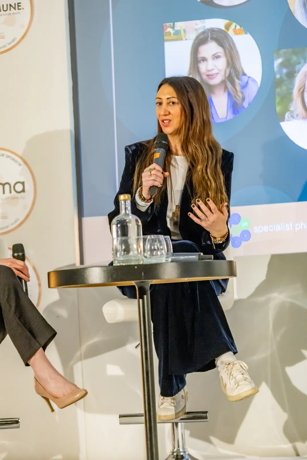 Lauren Vaknine speaking into a microphone on a panel stage