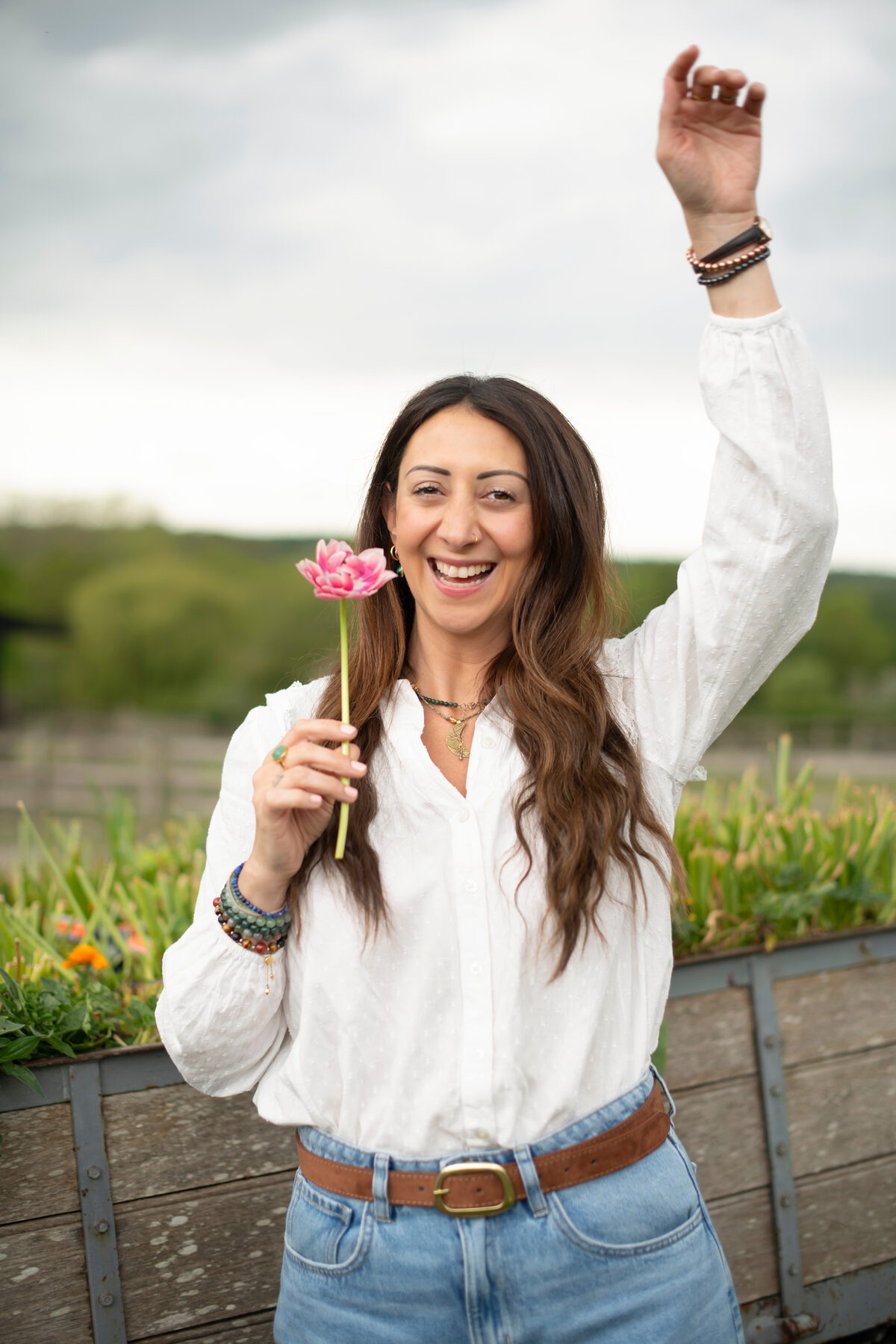 Lauren smiling in a white blouse, holding a pink flower