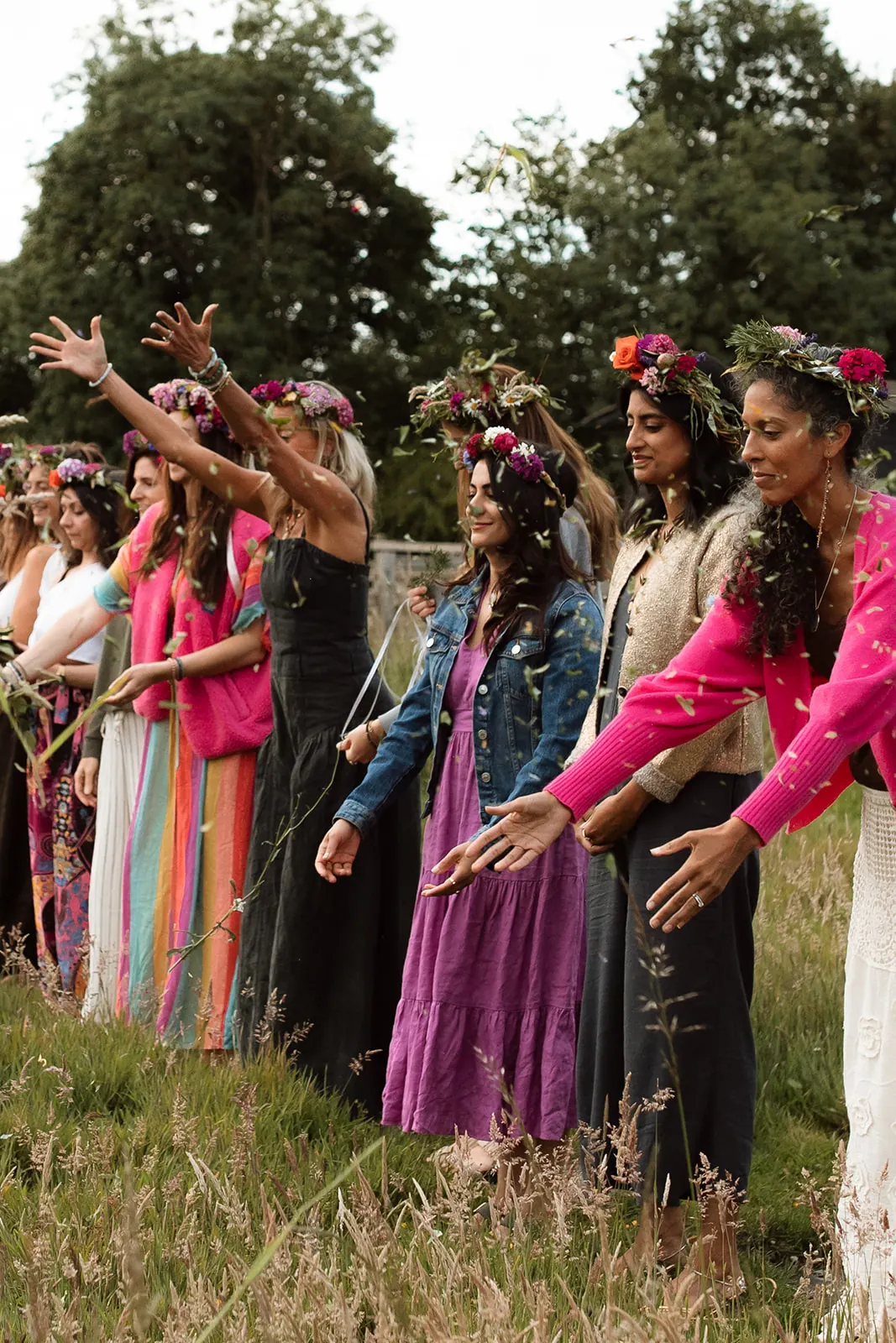 Women in flower crowns reaching their hands out together at a RISE retreat